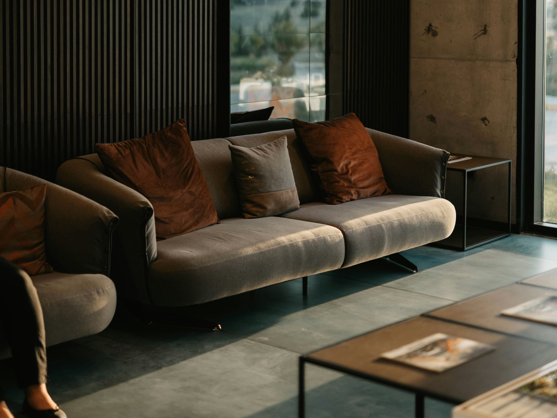 Moody living room with a grey sofa, rust velvet cushions and tall windows